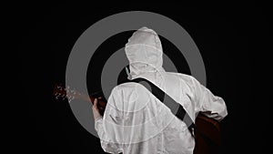 A man in a chemical protection suit plays the guitar