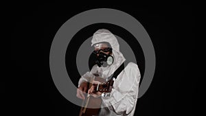 A man in a chemical protection suit plays the guitar