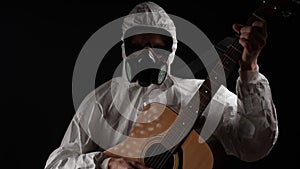 A man in a chemical protection suit plays the guitar