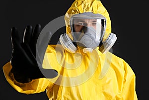 Man in chemical protective suit making stop gesture on background. Virus research