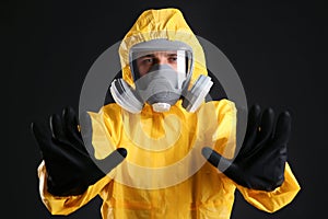 Man in chemical protective suit making stop gesture on background. Virus research