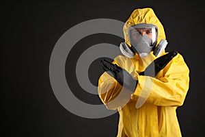 Man in chemical protective suit making stop gesture on black background. Virus research