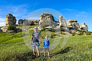 A man with a child on the background of a picturesque view of the Bakhchisarai sphinxes. Bakhchisarai. May 2021