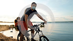 Man with a child on a bicycle in protective masks