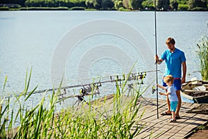 Man and child boy fishing with rods from wooden pier