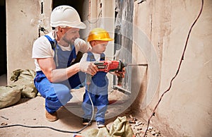 Man and child drilling wall with hammer drill in apartment.