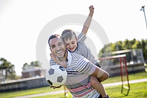 Man with child playing football on field