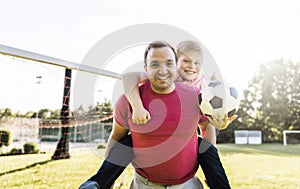 Man with child playing football outside on field