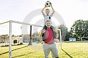 Man with child playing football outside on field