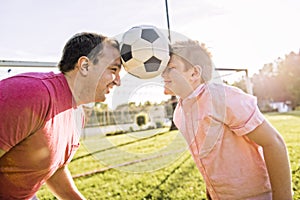 Man with child playing football outside on field