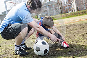 Man with child playing football on pitch