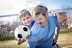 Man with child playing football on pitch