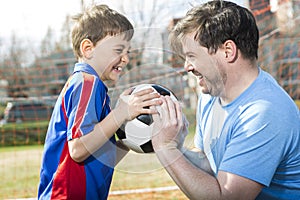 Man with child playing football on pitch