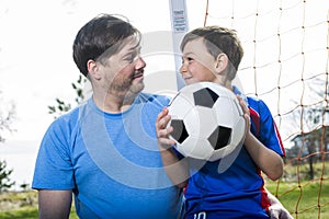 Man with child playing football on pitch