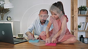 A man and a child are playing Poppit. A man working at a laptop takes a break and plays Poppit with a girl. Anti-stress toy