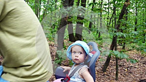 A man with a child riding a bicycle in the forest, in the summer, the child is sitting in a special chair