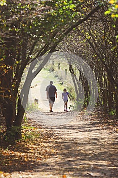 A man and child walking down a wooded forest trail