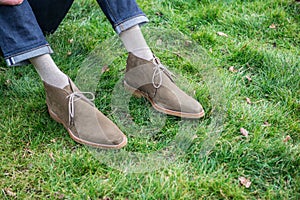 Man chilling on green grass wearing shoes and jeans.