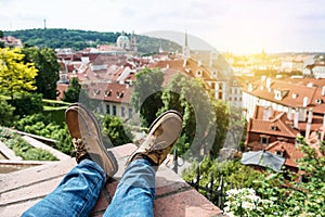 Man chilling on the rooftop sitting on the edge wearing leather shoes and enjoy the view of old town Prague, Czech Republic.