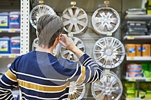 Man chooses alloy wheels for your car wheels in supermarket