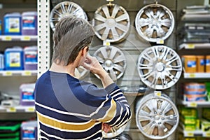 Man chooses alloy wheels for your car wheels in supermarket