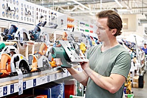 Man chooses electric saws in shop