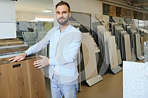 Man chooses floorboard laminate for home renovation in store