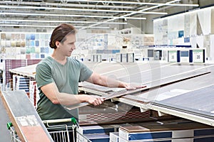 Man chooses floorboard laminate in store