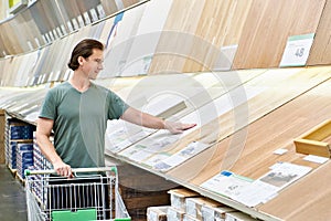 Man chooses floorboard laminate in store