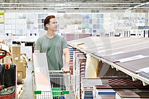 Man chooses floorboard laminate in store