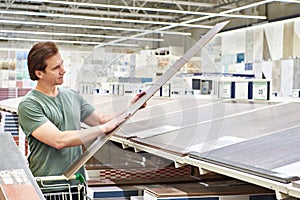 Man chooses floorboard laminate in store