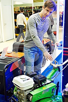 Man chooses garden tiller at hardware store