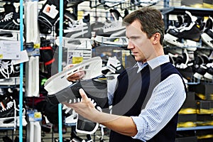 Man chooses hockey skates in sports shop