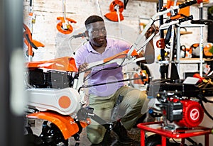 Man choosing cultivator in gardening tools store