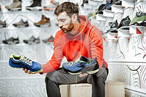 Man choosing hiking shoes in the shop