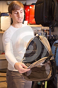 Man choosing knapsack among assortment in store