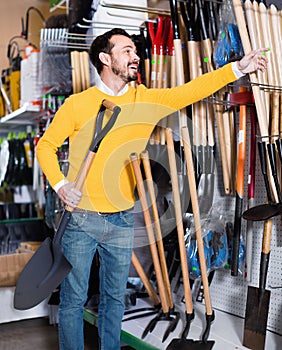 Man choosing new shovel in garden equipment shop