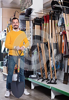 Man choosing new shovel in garden equipment shop