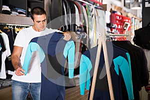 Man choosing new wetsuit in shop