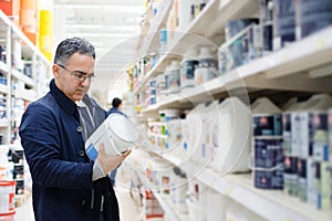 Man choosing paint on the shelves of a hardware store