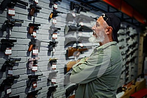 Man choosing pistol at the showcase in gun store