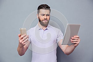 Man choosing between tablet computer and smartphone