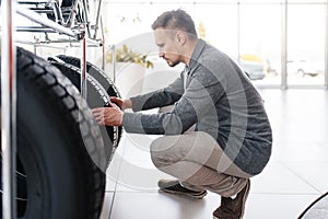 Man choosing tyres for new car in showroom