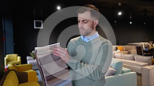 A man choosing upholstery fabric color and texture from various colorful samples for sofa in a store