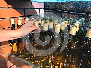 Man choosing white wine bottle at local winery - traditional homemade wine or alcohol fruit drinks in local wine store. Wine