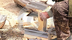 A man is chopping logs with an axe on chopping block. Harvesting of firewood stocks for heating.