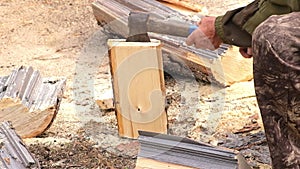 A man is chopping logs with an axe on chopping block. Harvesting of firewood stocks for heating.