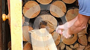 A man is chopping logs with an axe on chopping block. Harvesting of firewood stocks for heating.