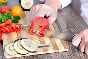 Man chopping paprika on cutting board with knife in kitchen