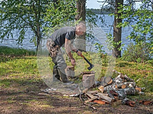 Man chopping wood for cooking at the stake. Ecotourism, visiting fragile, undisturbed natural